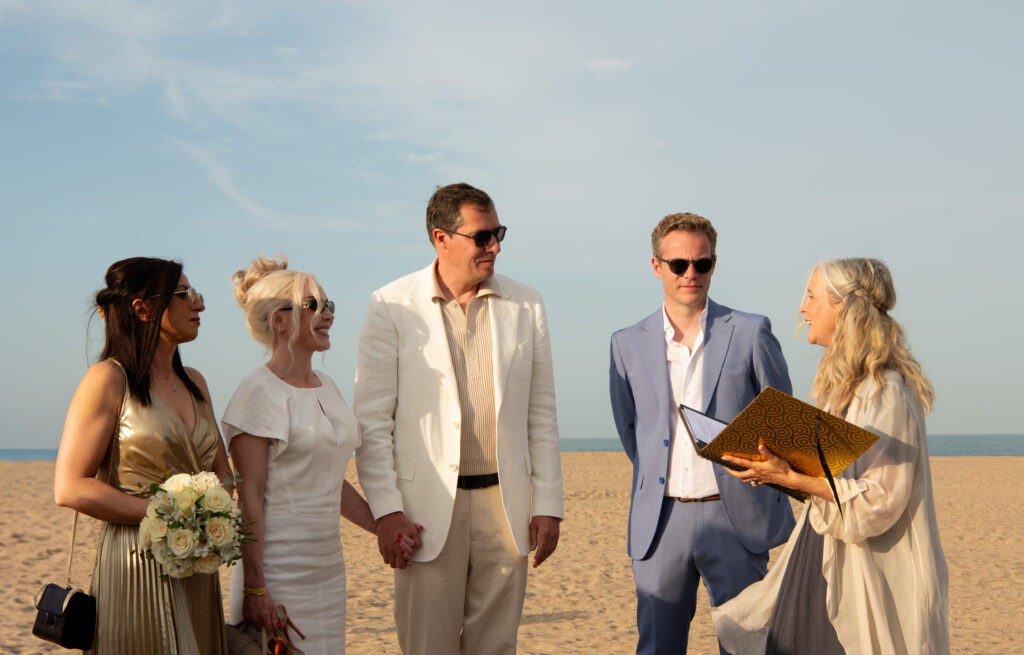 Wedding ceremony on the beach at Valencia’s Marina, with a celebrant leading a relaxed, intimate moment between the couple and their guests under clear skies